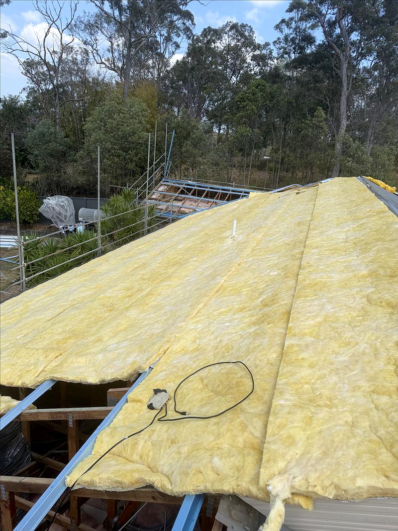 Roof blanket insulation being laid over the steel battens