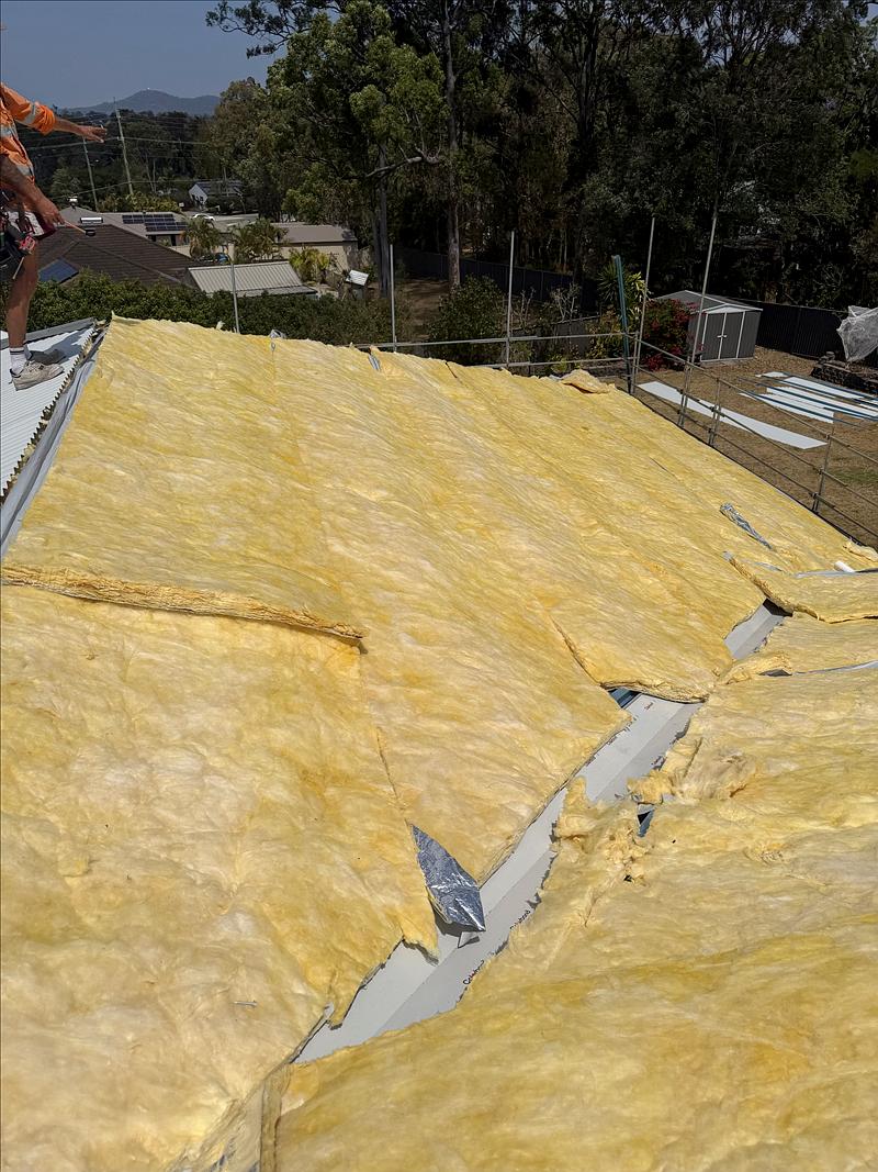 Roofer setting out the next run of sheets over the insulation and Colorbond valleys